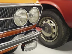 Two classic cars, one in orange and one in red