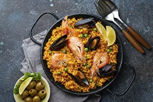 Classic dish of Spain, seafood paella in traditional pan on rustic blue concrete background top view
