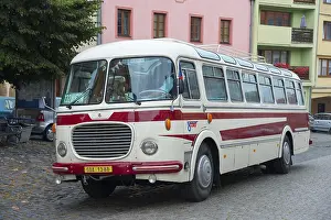 A classic old bus on a cobbled street in a town with colourful buildings