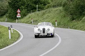 Classic white car on a winding road in a green landscape