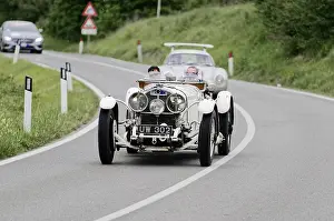A classic white vintage racing car on a winding country road