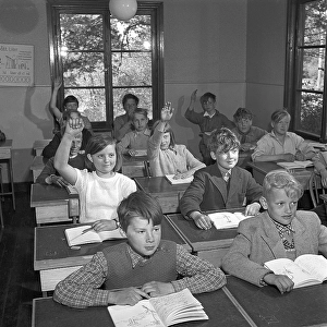 A classroom in 1952. Interior of a classroom where a class is sitting neatly in their school desks. The desks had a lid that could be opened. In the drawer underneath, the schoolgirls kept their books, pencils and school supplies