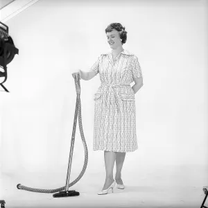 Cleaning day in the 1960s. A woman is standing holding a vacuum cleaner, looking happy. Sweden 1960. Kristoffersson ref CN109-11
