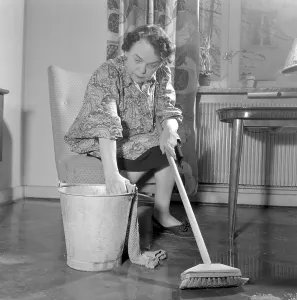 Cleaning the floor back then. A woman looks very tired and worn out when sitting on a chair
