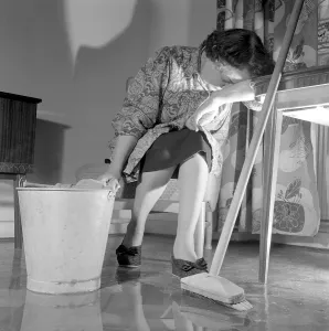 Cleaning the floor back then. A woman looks very tired and worn out when sitting on a chair