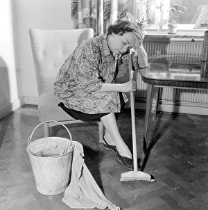 Cleaning the floor back then. A woman looks very tired and worn out when sitting on a chair