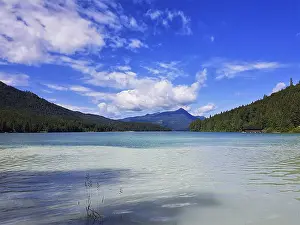 Framed Print : A clear lake with surrounding mountains and wooded slopes under a blue sky with white clouds Framed Print : A clear lake with surrounding mountains and wooded slopes under a blue sky with white clouds
