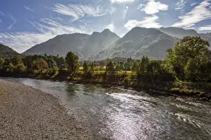 A clear river flows through an open landscape with a mountain in the background