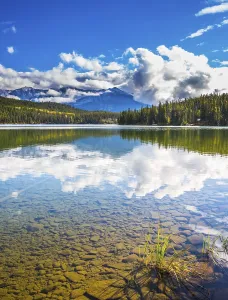 Clear water Pyramid Lake reflects the clouds and pine forests on shore