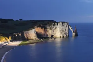 Cliffs with the Falaise d'Aval rock gate and the Aiguille d'Etretat rock needle at night