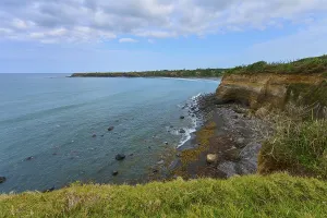 Cliffs above rocky shores in soft blue tones under a cloudy sky