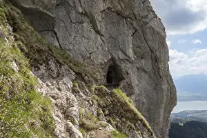 Cliffside cave and narrow hiking trail on Sigriswiller Rothorn in the Swiss Alps with panoramic lake and valley views