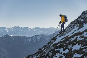 Climber on a ledge, snow-covered mountains