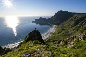 Climber on a rock, view of picturesque coastal landscape with sun star