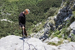 A climber in safety equipment descends a rocky mountain face