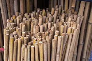 Close up full frame texture of vertical dry brown bamboo poles arranged as a natural fence