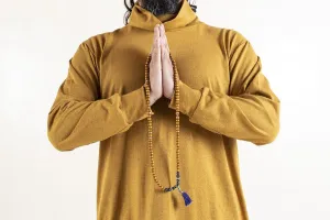 Close up of a man clasping hands while holding a japa mala over white background