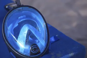 Close-up of a blue diving mask on a blue surface by the beach