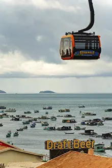 Close-up of a cable car over the sea with islands in the background under a cloudy sky
