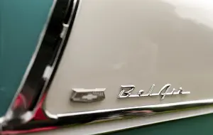 Close-up of a classic car emblem on a teal and cream colored body with chrome details in St