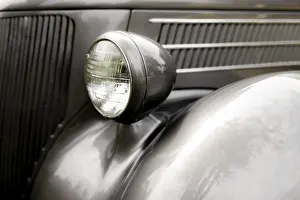 Close-up of a classic car's headlight in chrome on a black body in St