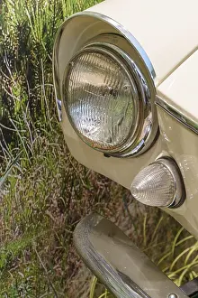 Close-up of a cream-coloured vintage car headlight against a green background