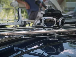 Close-up of a driver's goggles with reflection on the windscreen of a classic car against a blurred road