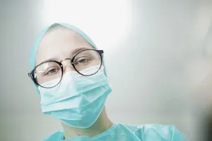 Close-up of a focused surgeon in mask and glasses