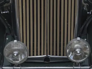Close-up of a green vintage car with vertical radiator grille and round headlights