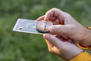 Close-up of a man with compass exploring natural environment