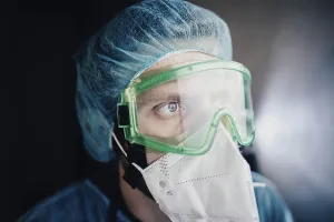 Close-up of a medical professional wearing green goggles and a mask