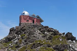 Close-up of a red observatory on a rocky hill under a blue sky