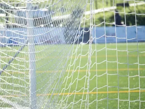 Close-up of a soccer goal net with a focus on the grid pattern under bright sunlight