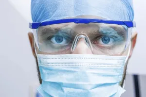 Close-up of a surgeon with intense eyes behind glasses