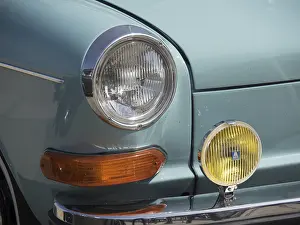 Close-up of the front of a turquoise classic car with orange and yellow headlights