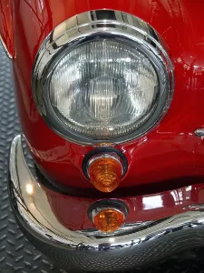 Close-up of a vintage car headlight with red details