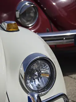 Close-up of a white vintage car with red car in the background
