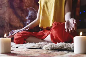 Close-up of woman's hand in yoga lotus pose meditating in a crafting room with candles<br> Close-up of woman's hand