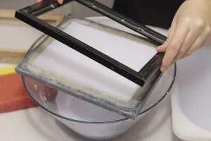 Close-up of a woman's hands making handmade paper at home from recycled materials<br> Close-up of a woman's hands
