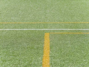 A close up view of vibrant green artificial turf with distinct yellow and white lines