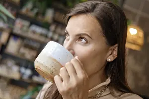 Closeup portrait of beautiful girl drinking coffee and looking to the window of cafeteria