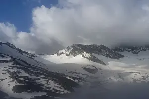 Cloudy, atmospheric mountain landscape with glaciated mountain peaks