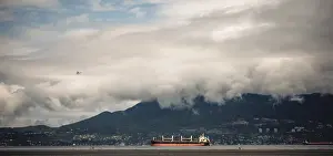 Cloudy sky over mountains with cargo ships on the ocean