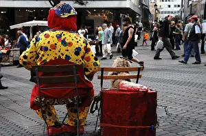 Clown with his dog sitting in a pedestrian area