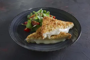 Club sandwich with melted cheese inside served with tomato cherry and salad