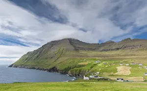 Coastal landscape with mountains and village under blue sky