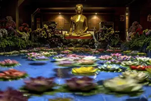 Colorful flowers floating under the golden statue of Buddha in Buddhist monastery