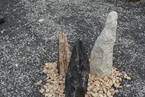 Three colorful standing stones arranged in a circle of pebbles on a grey gravel background