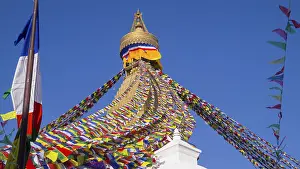 Colourful prayer flags surround the golden tip of a stupa