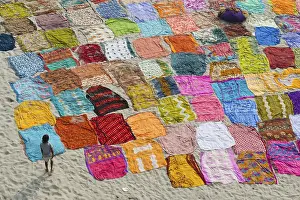 Colourful saris laying to dry after washing on a sandbank on the banks of the Yamuna River